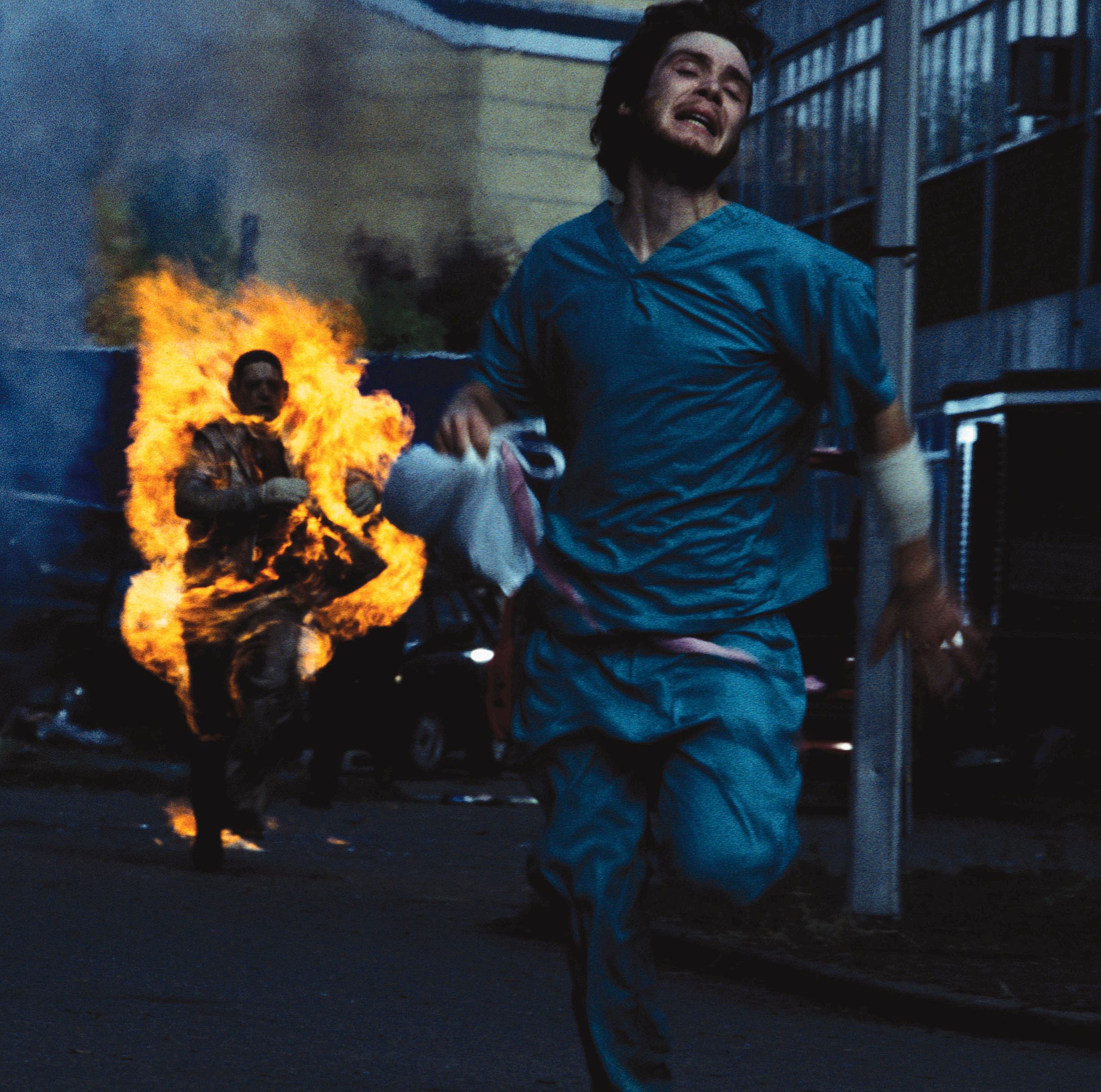 Cillian Murphy runs away from someone on fire in a scene from 28 Days Later