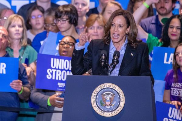 Vice President Kamala Harris speaking at a podium during a campaign event at IBEW Local Union #5 in Pittsburgh, Pennsylvania.